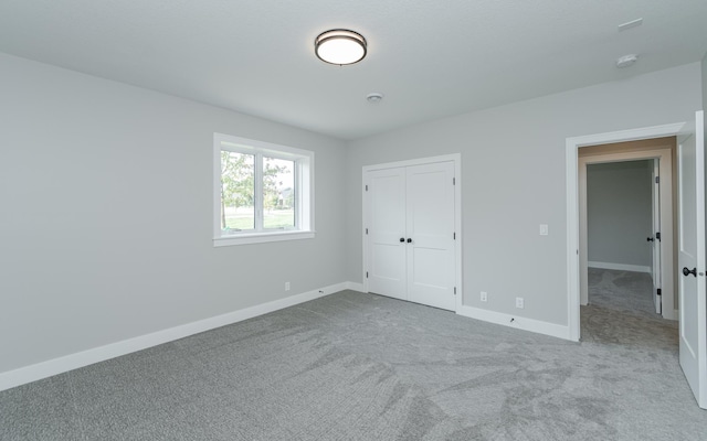 unfurnished bedroom featuring light carpet and a closet