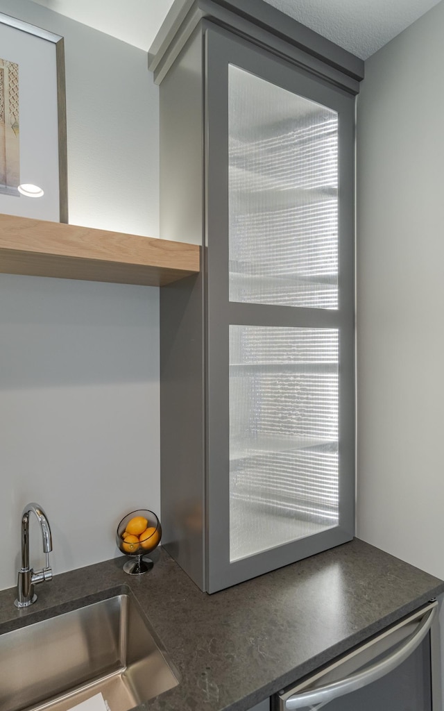 room details featuring stainless steel dishwasher, a textured ceiling, and sink