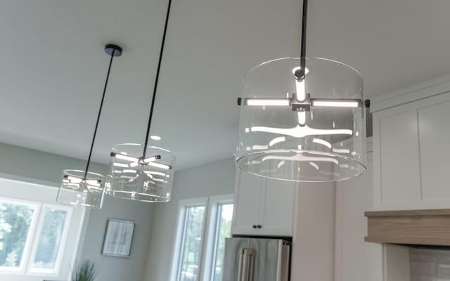 interior details featuring an inviting chandelier, stainless steel refrigerator, and white cabinets