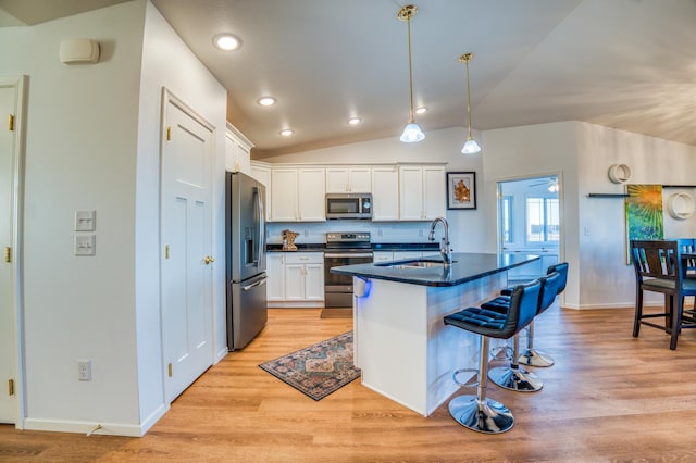 kitchen with stainless steel appliances, a kitchen bar, an island with sink, and white cabinets