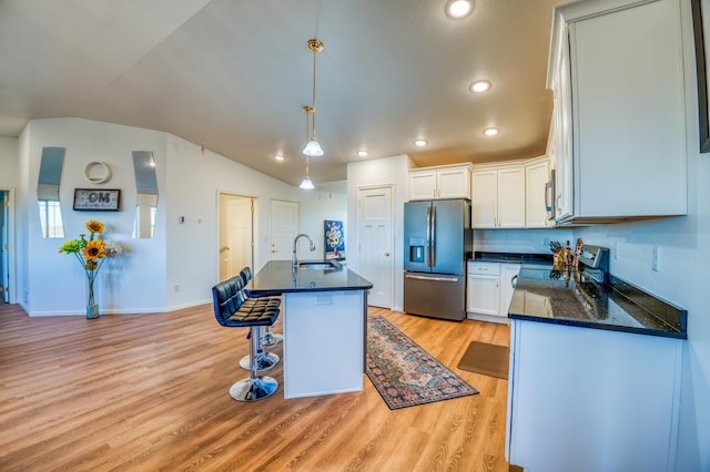 kitchen featuring sink, decorative light fixtures, appliances with stainless steel finishes, a kitchen island with sink, and white cabinets