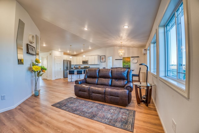 living room with vaulted ceiling, light hardwood / wood-style flooring, and a notable chandelier