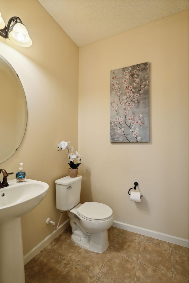 bathroom featuring tile patterned flooring, sink, toilet, and a textured ceiling