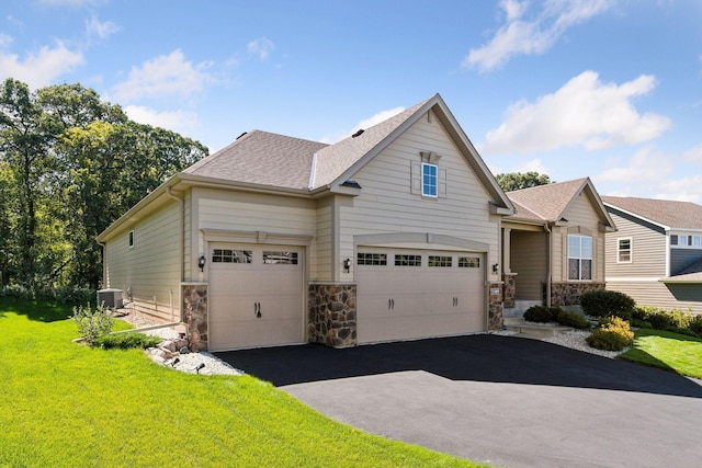 view of front of property featuring a garage, a front yard, and central AC