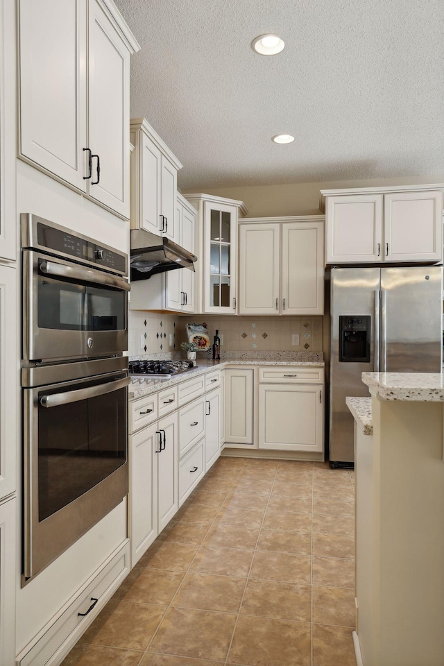 kitchen featuring white cabinets, backsplash, light tile patterned floors, and stainless steel appliances