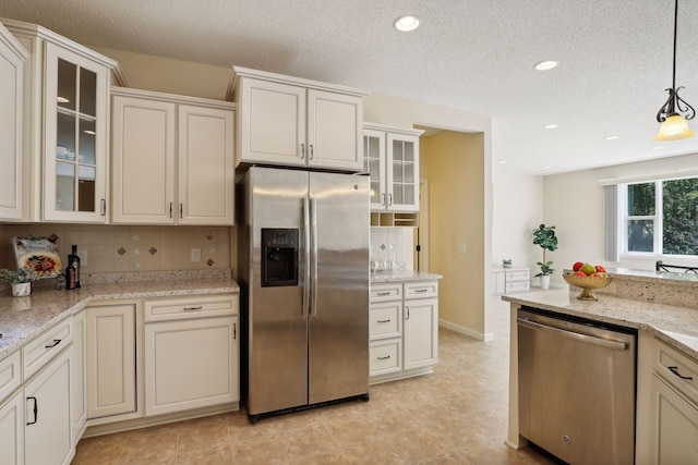 kitchen featuring pendant lighting, decorative backsplash, a textured ceiling, light stone counters, and stainless steel appliances