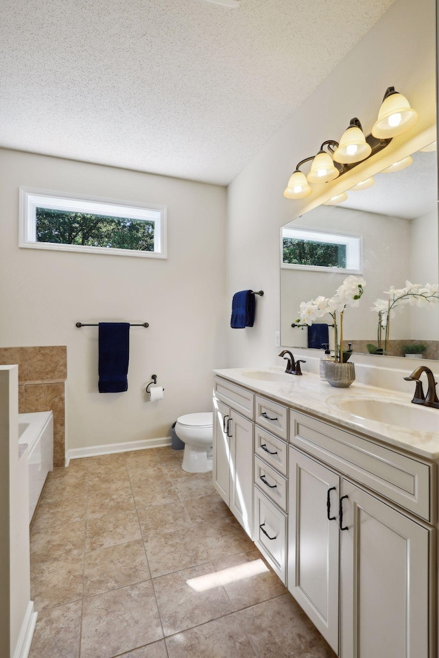 bathroom with a washtub, a textured ceiling, vanity, tile patterned flooring, and toilet