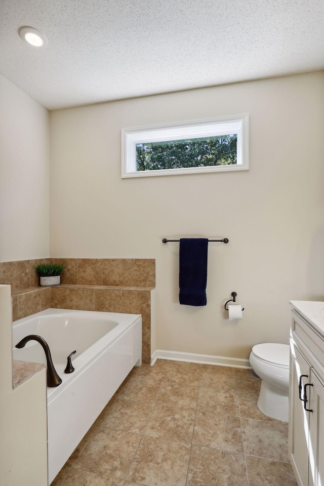 bathroom featuring vanity, a bath, a textured ceiling, and toilet