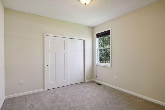 unfurnished bedroom featuring a closet and light colored carpet