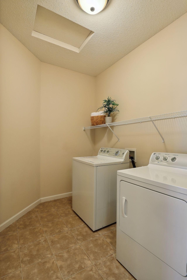 washroom featuring washing machine and clothes dryer, tile patterned floors, and a textured ceiling