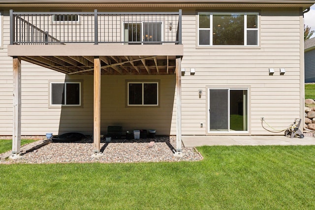 rear view of property featuring a lawn, a patio area, and a wooden deck