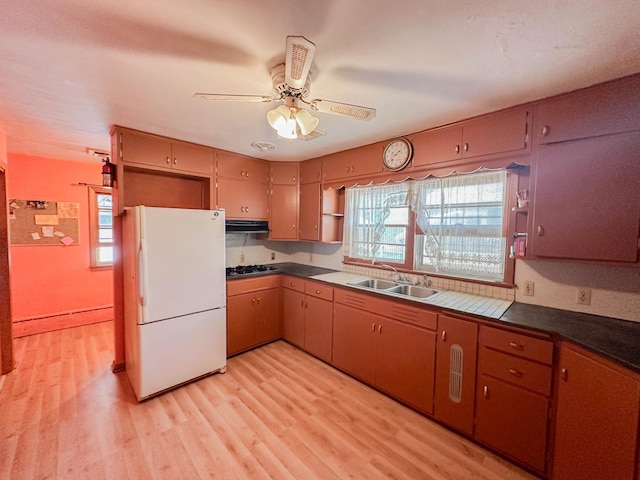 kitchen with light hardwood / wood-style floors, sink, stainless steel gas stovetop, white fridge, and ceiling fan