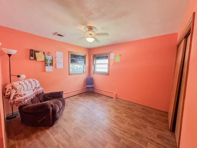 living area with wood-type flooring, a baseboard radiator, and ceiling fan