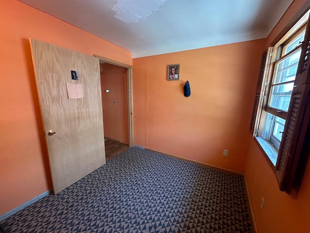 unfurnished room featuring dark colored carpet