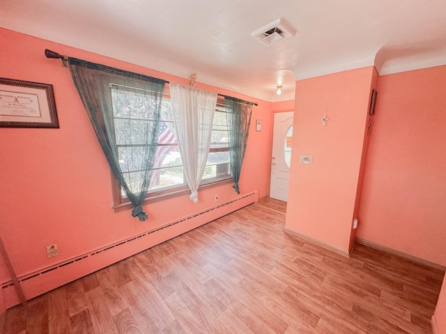 unfurnished room with a baseboard radiator and light wood-type flooring