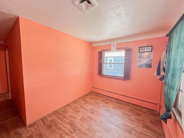 unfurnished room with a baseboard radiator and light wood-type flooring