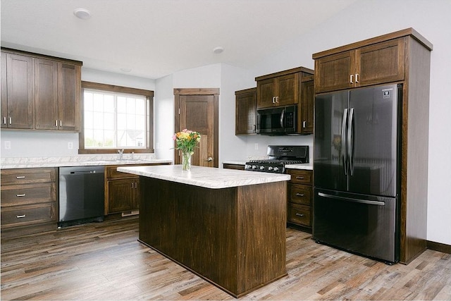 kitchen with black appliances, light wood-type flooring, dark brown cabinetry, and a center island