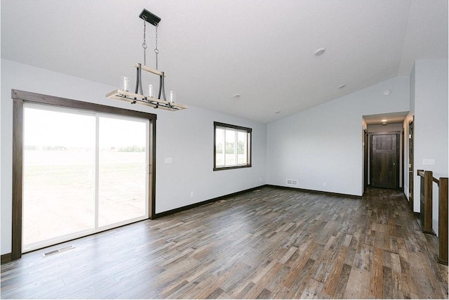 spare room with vaulted ceiling, wood finished floors, visible vents, and baseboards