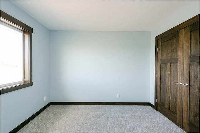 unfurnished bedroom with a closet, carpet flooring, and baseboards