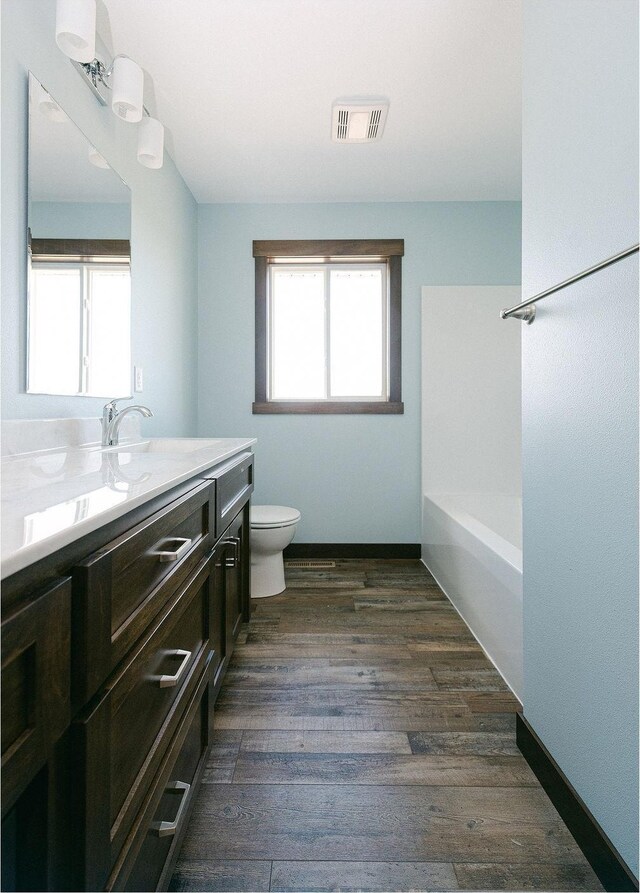 bathroom featuring visible vents, toilet, wood finished floors, baseboards, and vanity