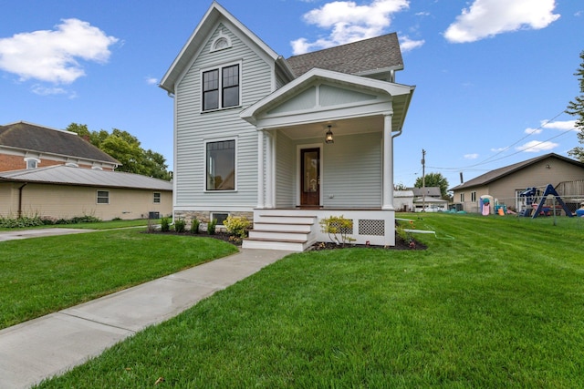 victorian home with a front yard, a porch, roof with shingles, and a playground