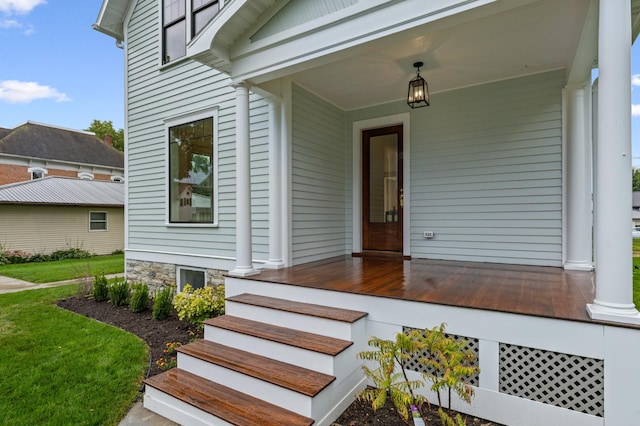 doorway to property featuring covered porch and a lawn