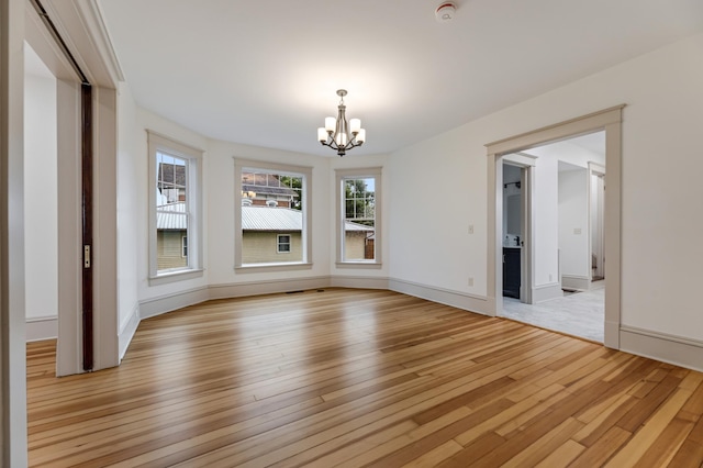 unfurnished dining area featuring baseboards, a chandelier, and light wood-type flooring