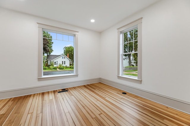 empty room with hardwood / wood-style flooring, recessed lighting, a healthy amount of sunlight, and visible vents