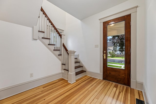 entrance foyer with a wealth of natural light, stairway, visible vents, and wood finished floors