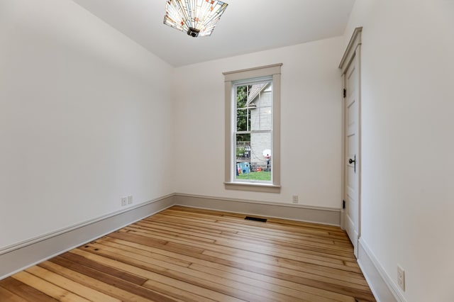 empty room featuring light wood finished floors, visible vents, and baseboards