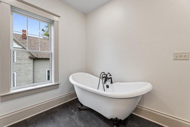 full bath featuring a soaking tub and baseboards