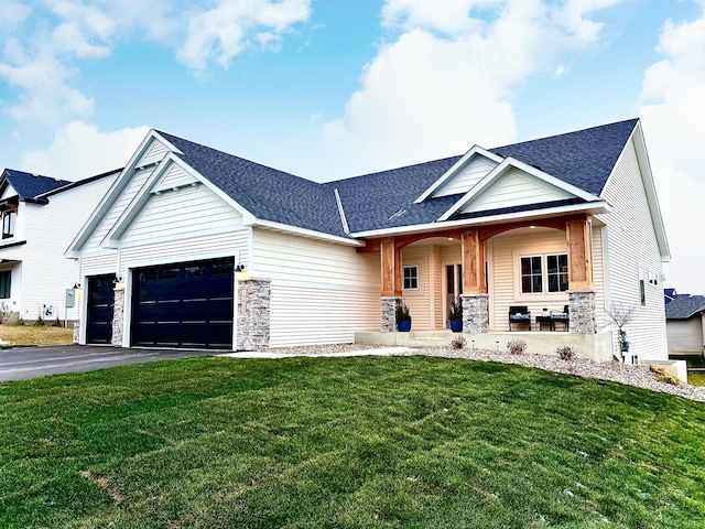 view of front of property featuring a front yard, covered porch, and a garage