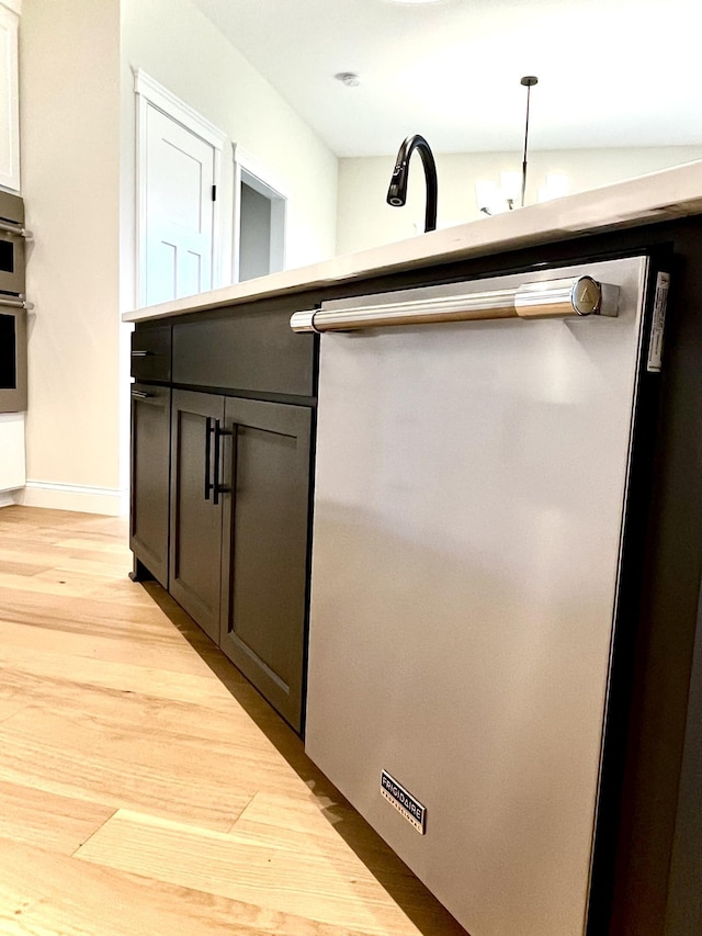 room details featuring sink, light hardwood / wood-style floors, and pendant lighting