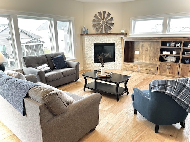 living room featuring light hardwood / wood-style floors, plenty of natural light, and a stone fireplace