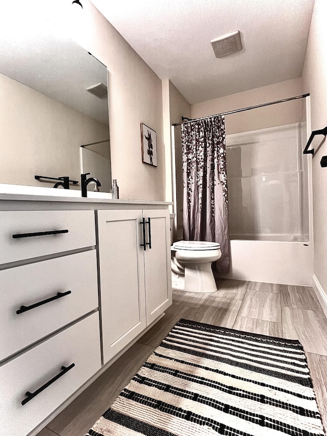 full bathroom with a textured ceiling, toilet, vanity, and shower / tub combo