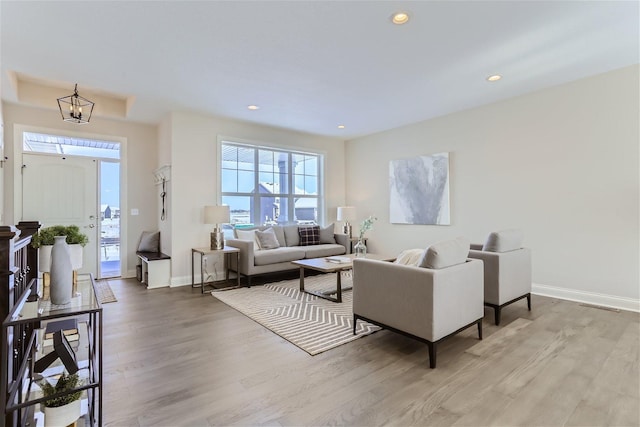 living room with plenty of natural light, wood-type flooring, and an inviting chandelier