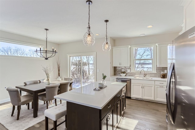 kitchen featuring a healthy amount of sunlight, light hardwood / wood-style flooring, appliances with stainless steel finishes, and white cabinetry