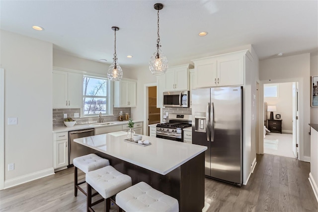 kitchen featuring a kitchen island, appliances with stainless steel finishes, light hardwood / wood-style floors, sink, and white cabinets