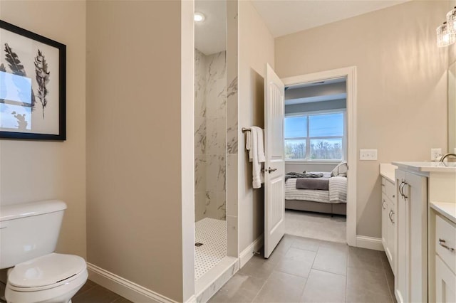 bathroom with tiled shower, vanity, toilet, and tile patterned flooring