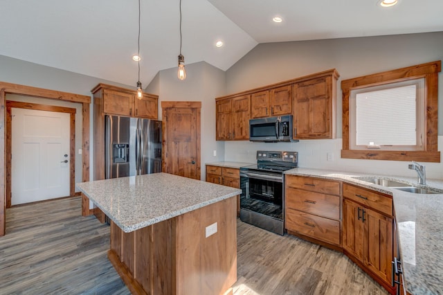 kitchen featuring pendant lighting, sink, a center island, stainless steel appliances, and light stone countertops