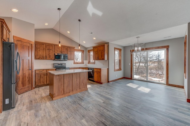 kitchen with pendant lighting, light hardwood / wood-style flooring, appliances with stainless steel finishes, light stone counters, and a kitchen island