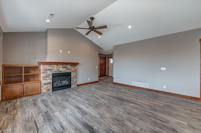 unfurnished living room with vaulted ceiling, wood-type flooring, a stone fireplace, and ceiling fan