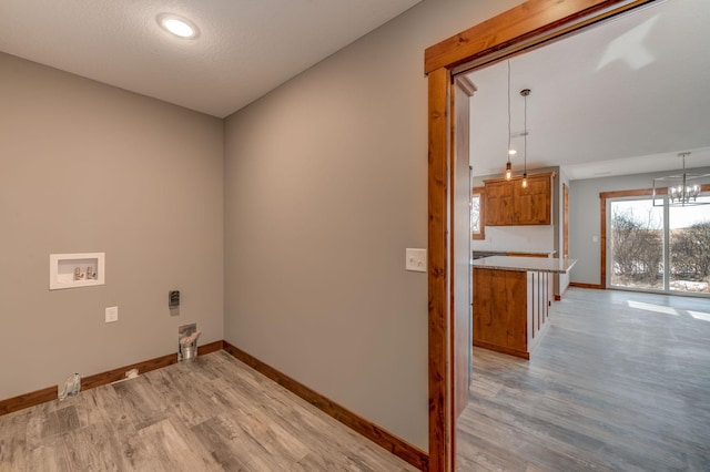 laundry area with washer hookup, a chandelier, a textured ceiling, and light hardwood / wood-style flooring