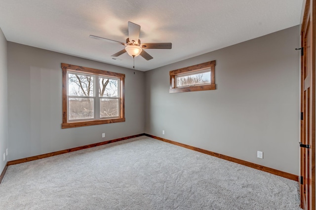 carpeted empty room featuring a textured ceiling, a wealth of natural light, and ceiling fan