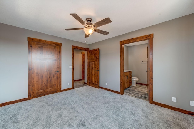 unfurnished bedroom featuring ceiling fan, light colored carpet, a closet, and ensuite bath