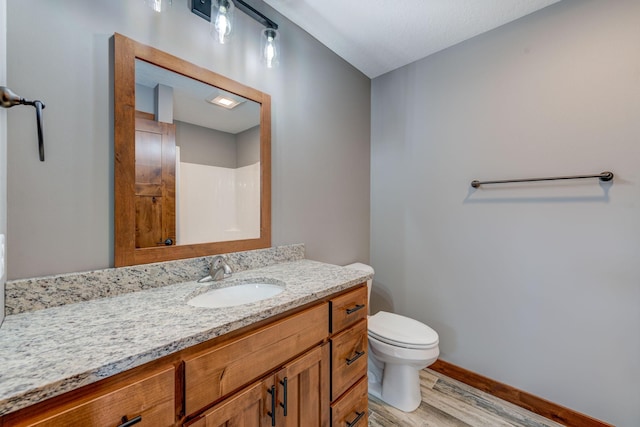 bathroom with wood-type flooring, walk in shower, vanity, and toilet