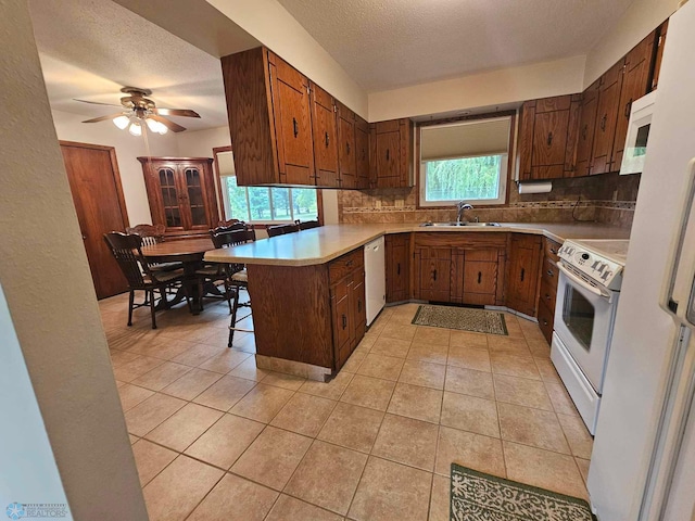 kitchen featuring a kitchen bar, sink, kitchen peninsula, white appliances, and backsplash