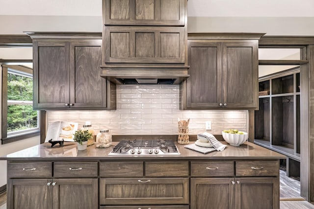 kitchen featuring dark brown cabinets, stainless steel gas stovetop, backsplash, and wood-type flooring