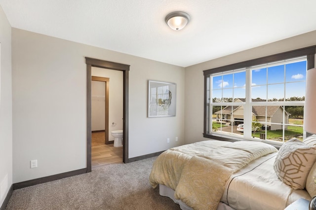 bedroom featuring ensuite bathroom and carpet flooring