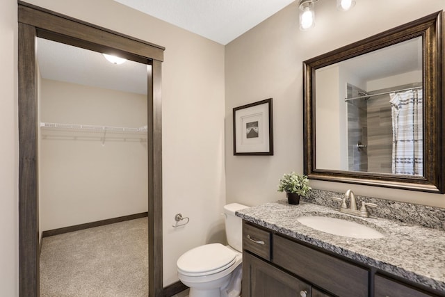 bathroom with walk in shower, toilet, and vanity